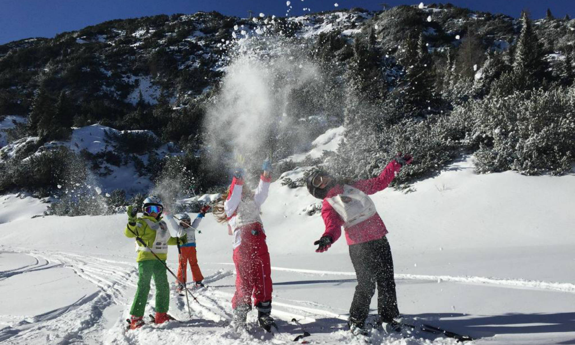 I partecipanti di un corso di sci ad Andalo lanciano la neve in aria.