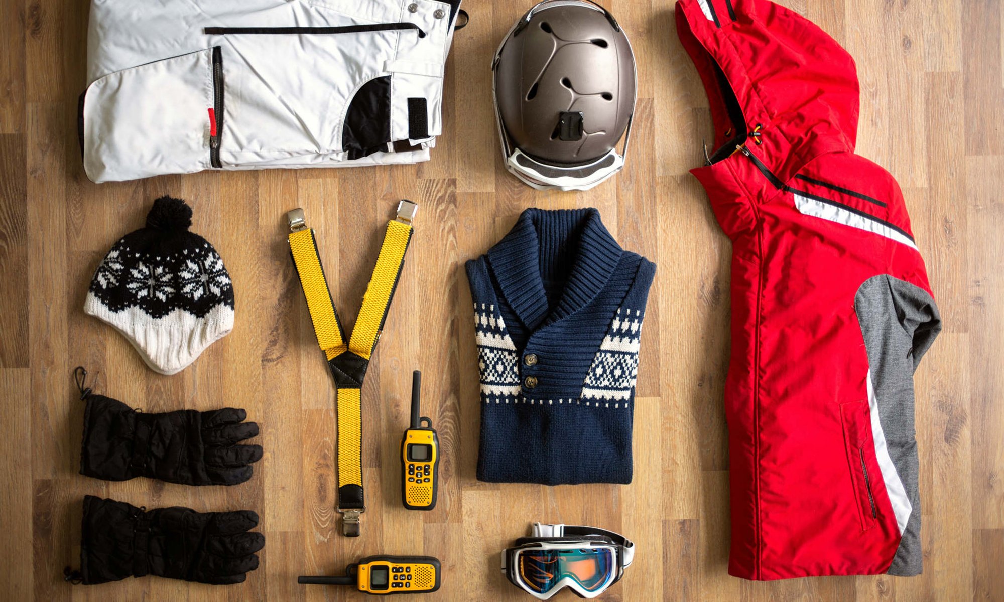 Een overzicht van alles wat je nodig hebt voor een perfecte dag op de piste zoals een skibroek en ski-jas, handschoenen, muts, skibril en een lekkere warme trui.