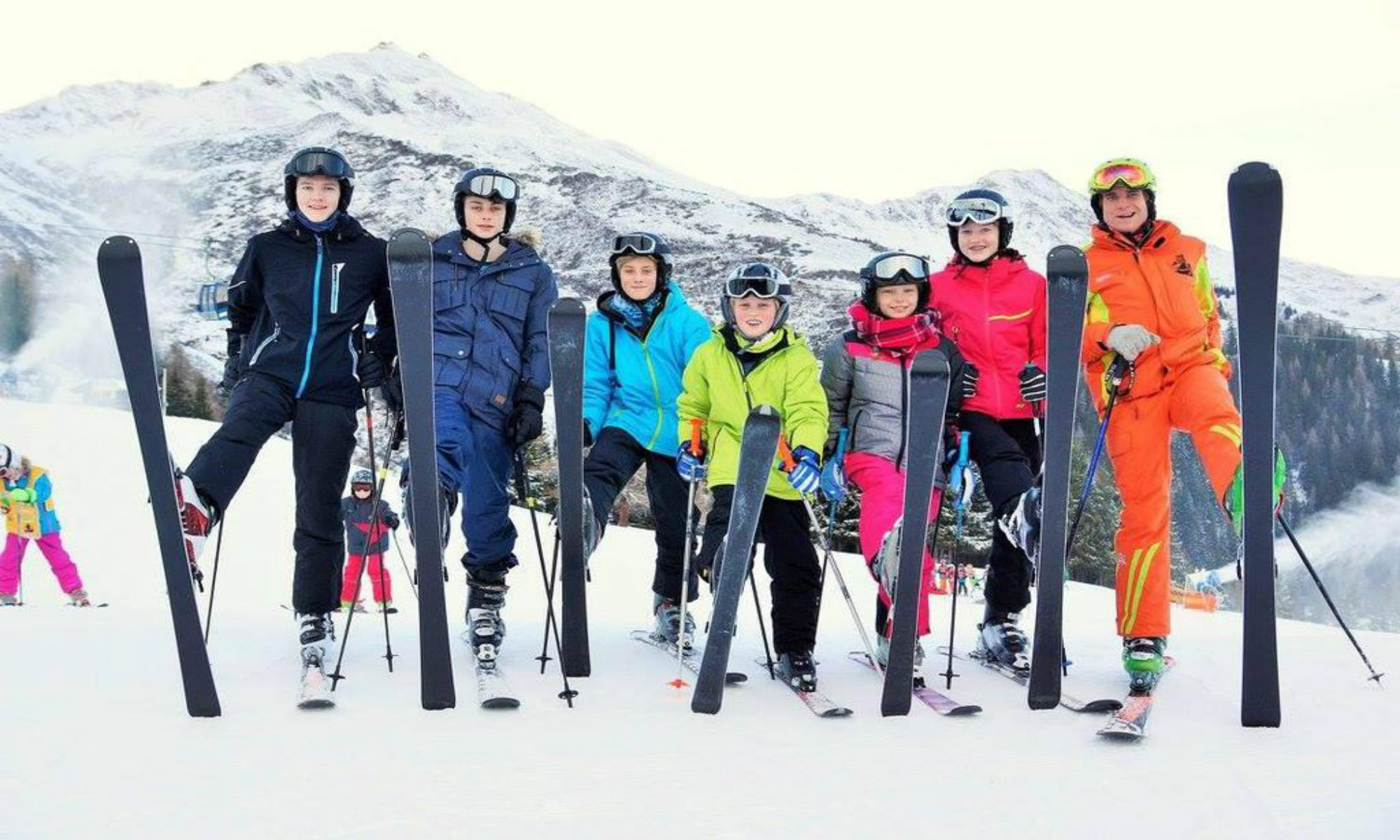 Een groep leerlingen poseert voor een foto met hun skileraar.