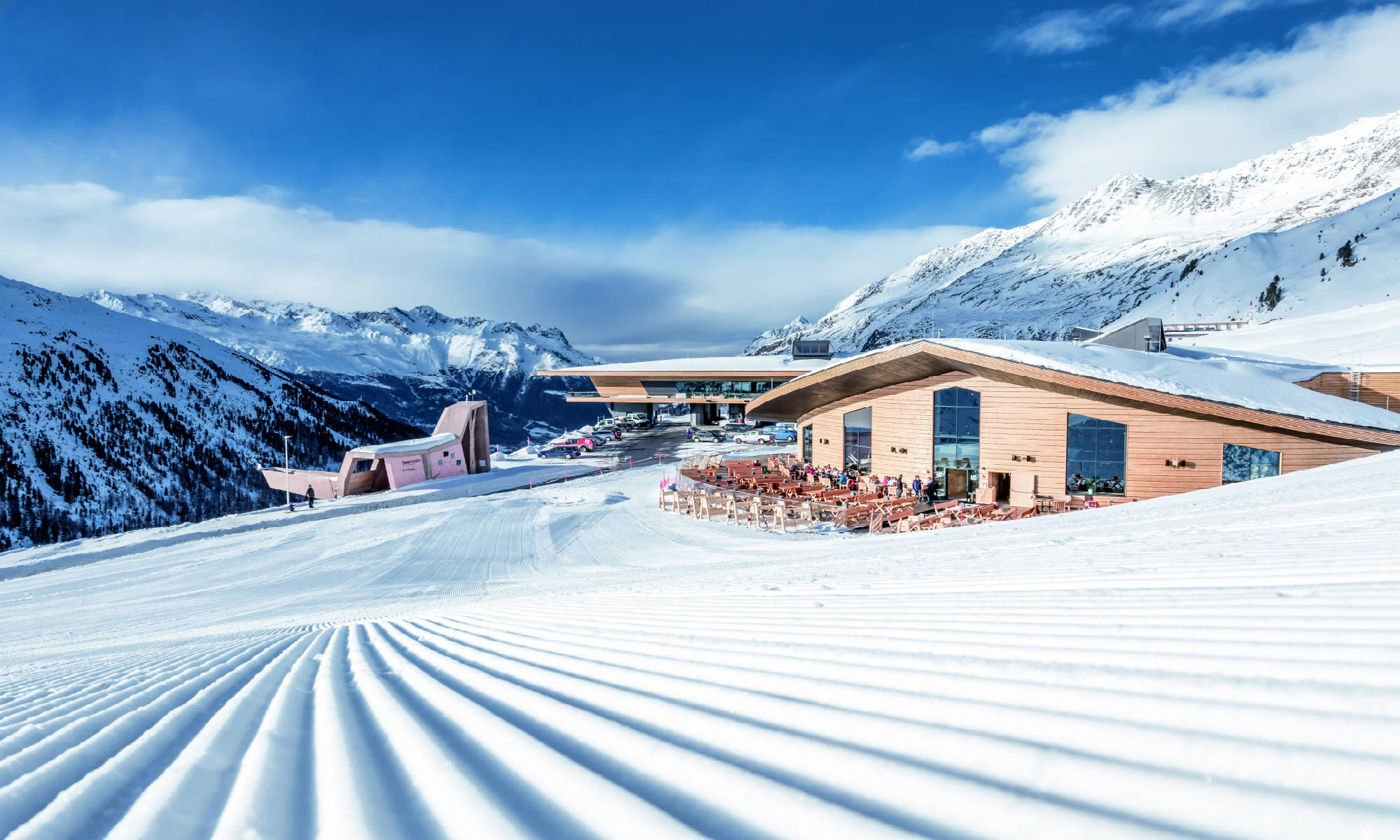 View of a mountaintop restaurant and the perfectly-groomed pistes of Obergurgl.