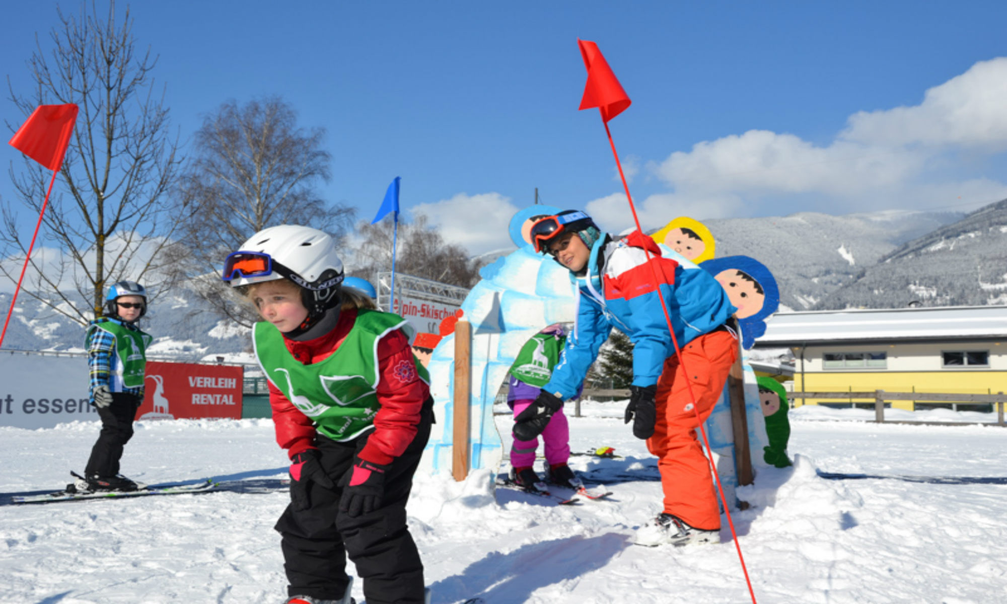 Een meisje is bezig met een ski-oefening onder het toeziend oog van haar skilerares. 