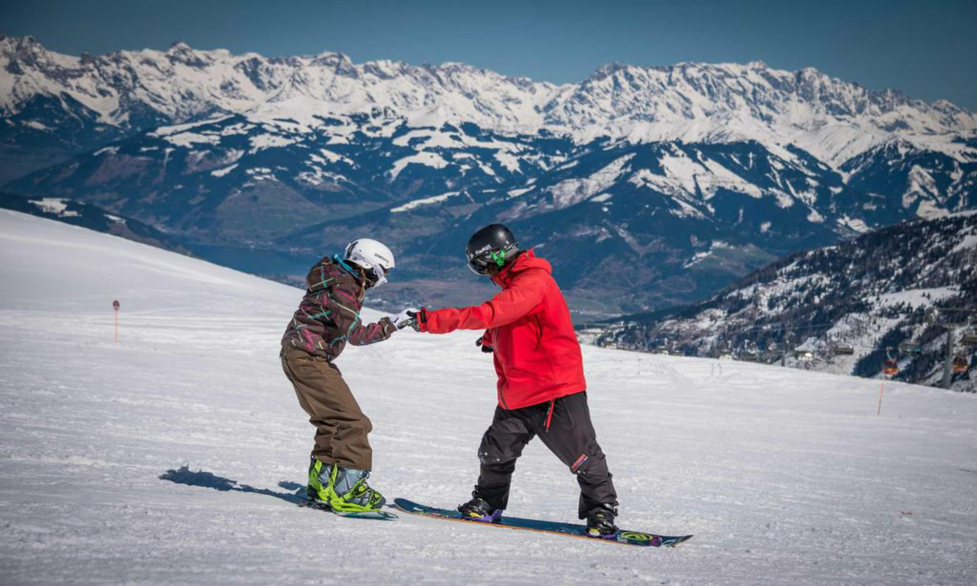 Een snowboardleraar helpt zijn leerling tijdens een snowboardles in het skigebied van Kaprun.