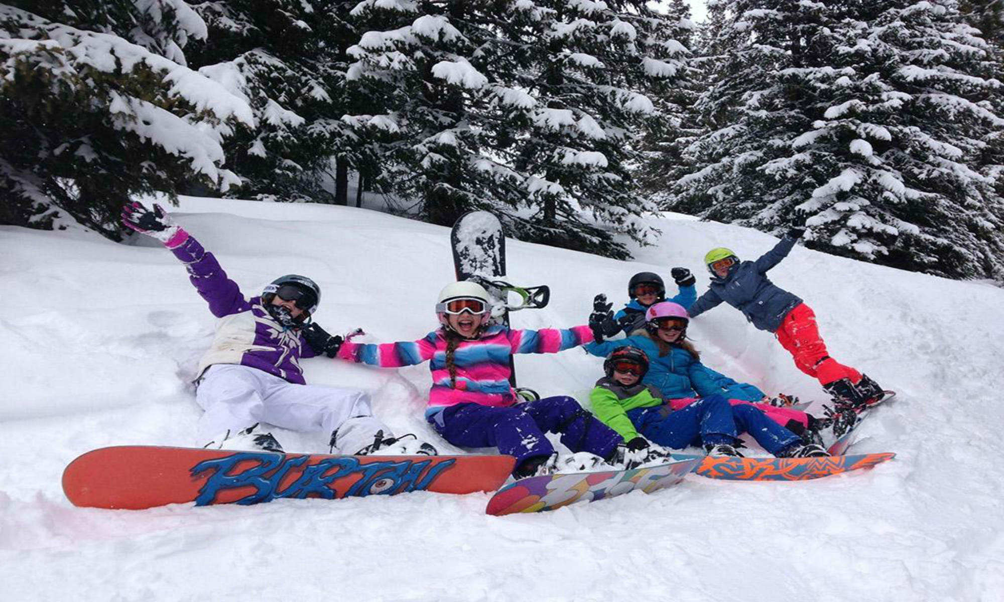 Een groep kinderen poseert in de sneeuw tijdens hun snowboardles in Saalbach.