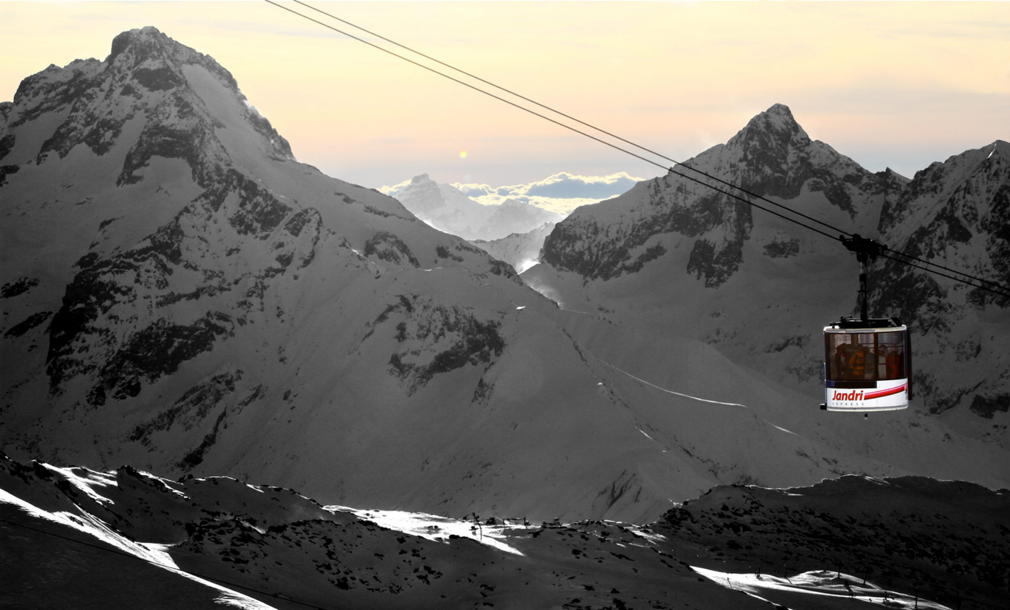 Vue sur la télécabine Jandri aux Deux Alpes, devant des sommets enneigés et un magnifique soleil couchant.