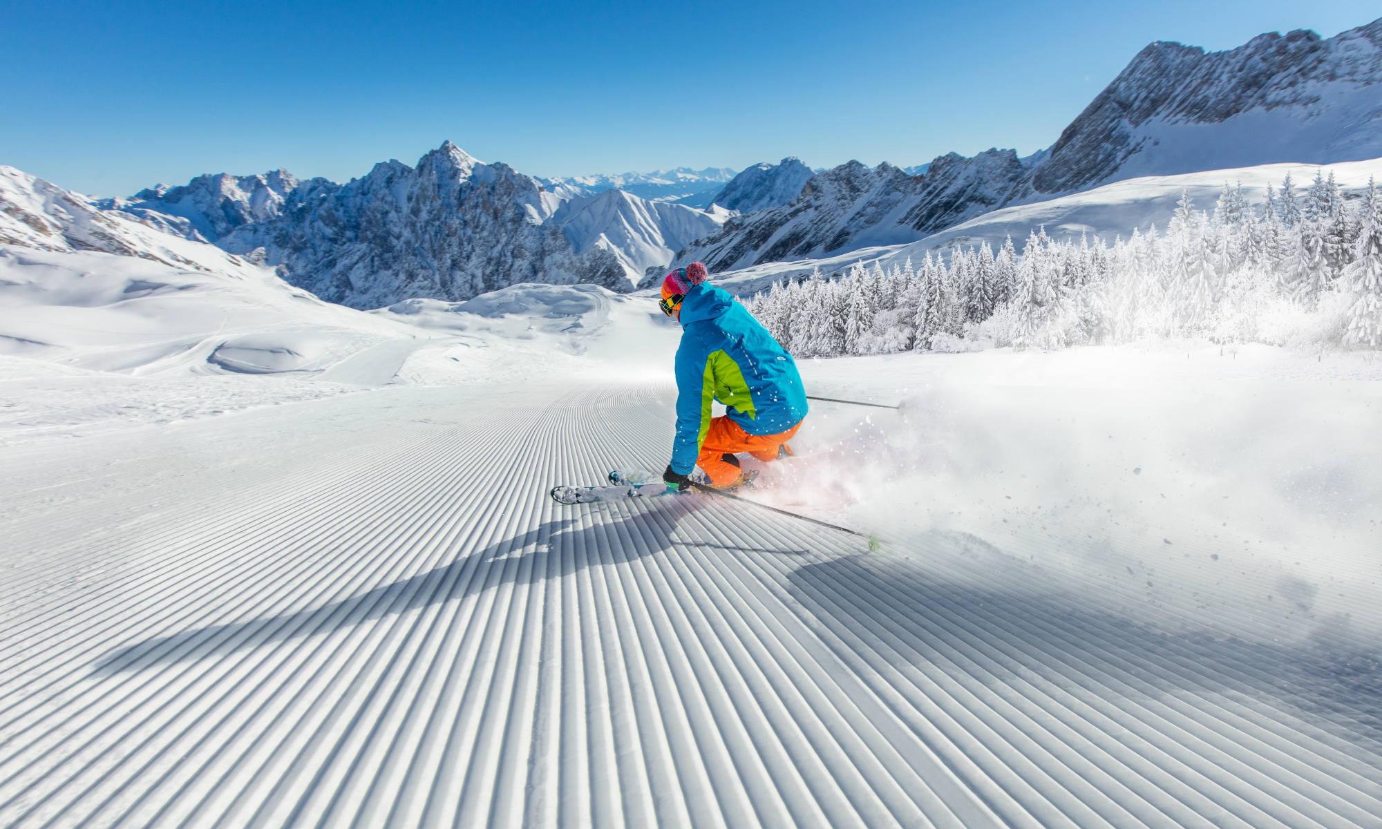 Uno sciatore scivola lungo una pista vuota, con le Dolomiti sullo sfondo.