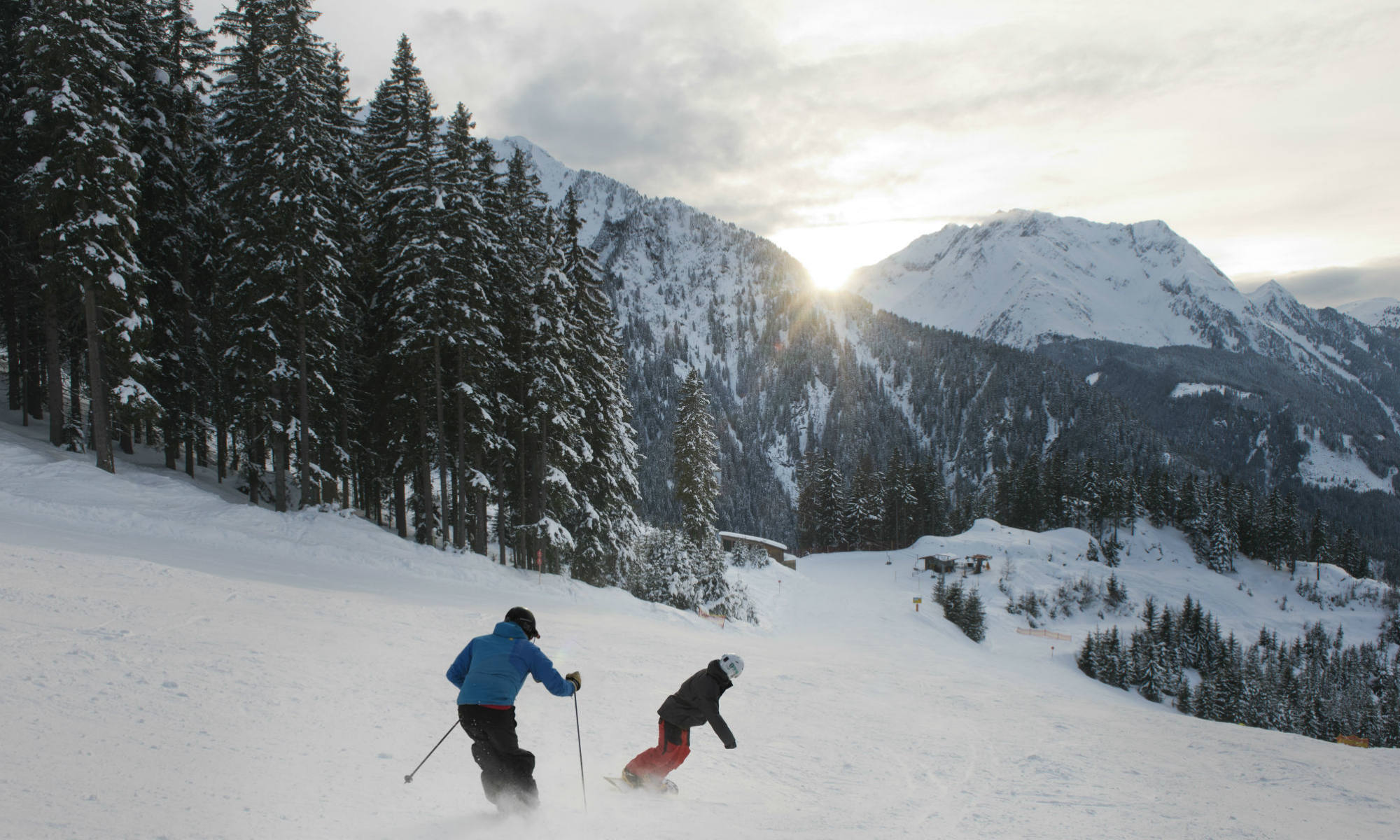 Een skiër en een snowboarder genieten van hun wintersport in Tirol tijdens een afdaling in het skigebied van Mayrhofen.