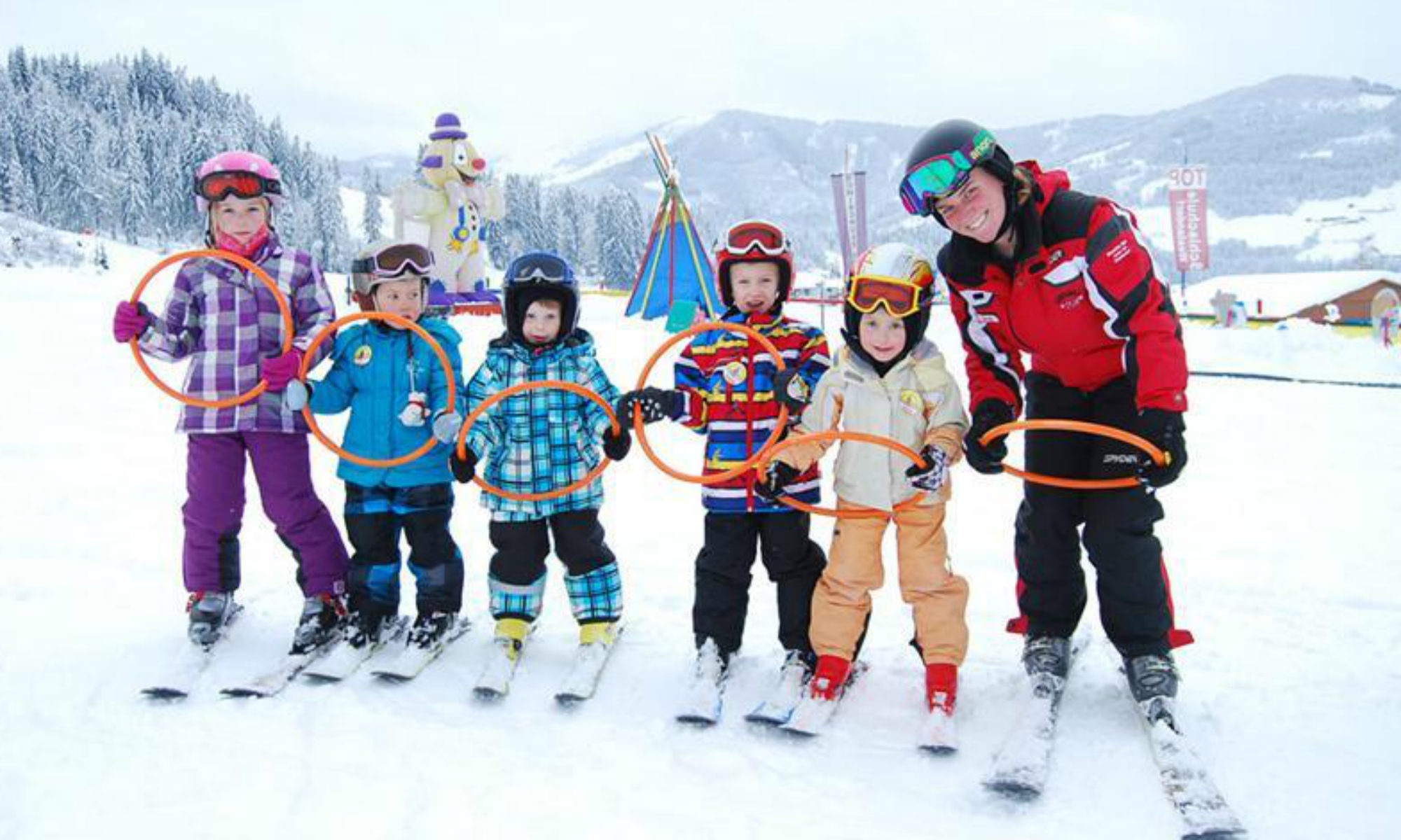 Een groep leerlingen poseert voor een foto met hun skilerares tijdens hun wintersport in Tirol.
