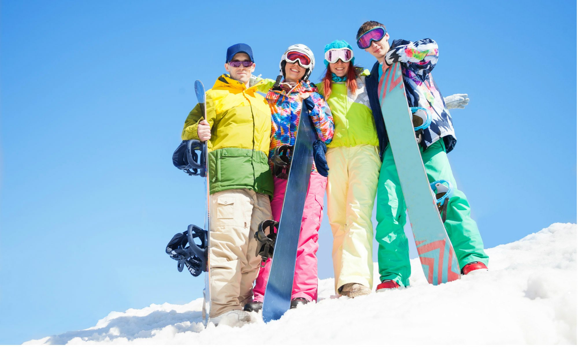 Un gruppo di amici in posa sulla neve con i loro snowboard.