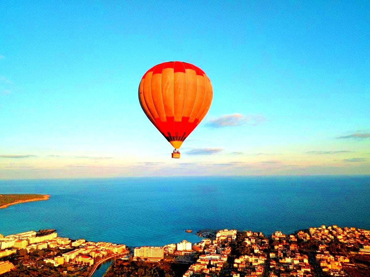 A hot air balloon flies over a town on the island of Mallorca.
