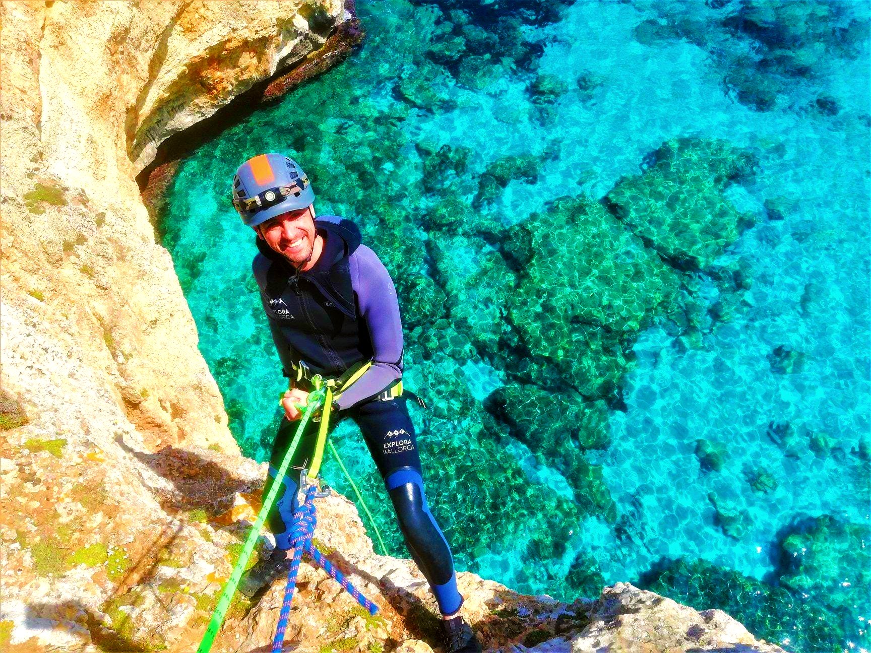 A guy is abseiling a cliff during Coasteering in Mallorca.