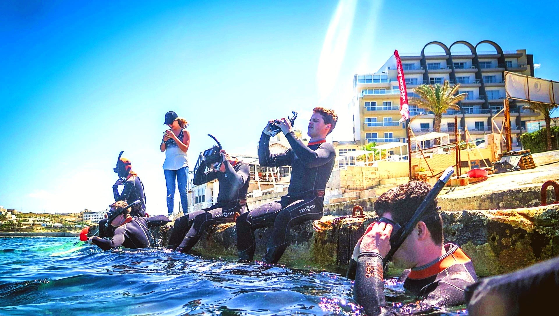 A group of 4 guys put the mask on their face before a snorkelling excursion in Malta.