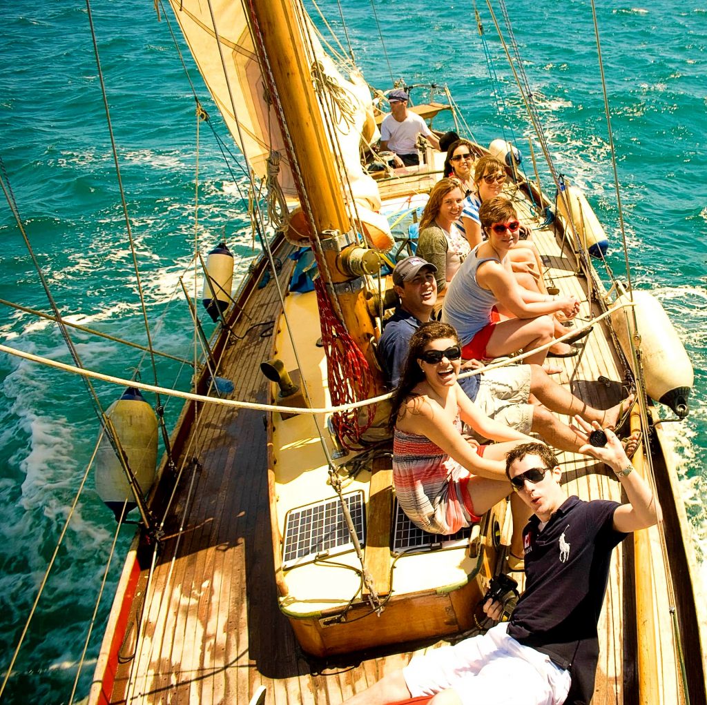 A group of friends have fun while admiring the beautiful Catalan landscape during a boat trip in Barcelona, a beautiful outdoor activity in Barcelona.