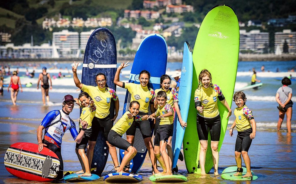 A group of kids is posing for a picture at the end of the surfing lesson for beginners in Hendaye.