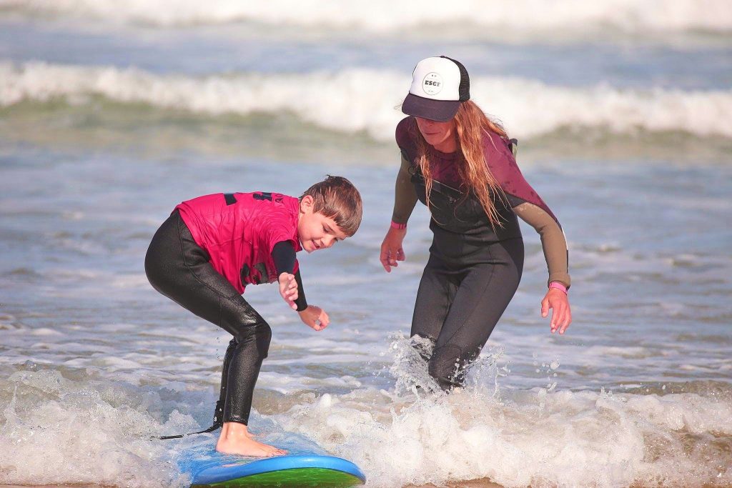 A kid is surfing in Anglet followed by his instructor.
