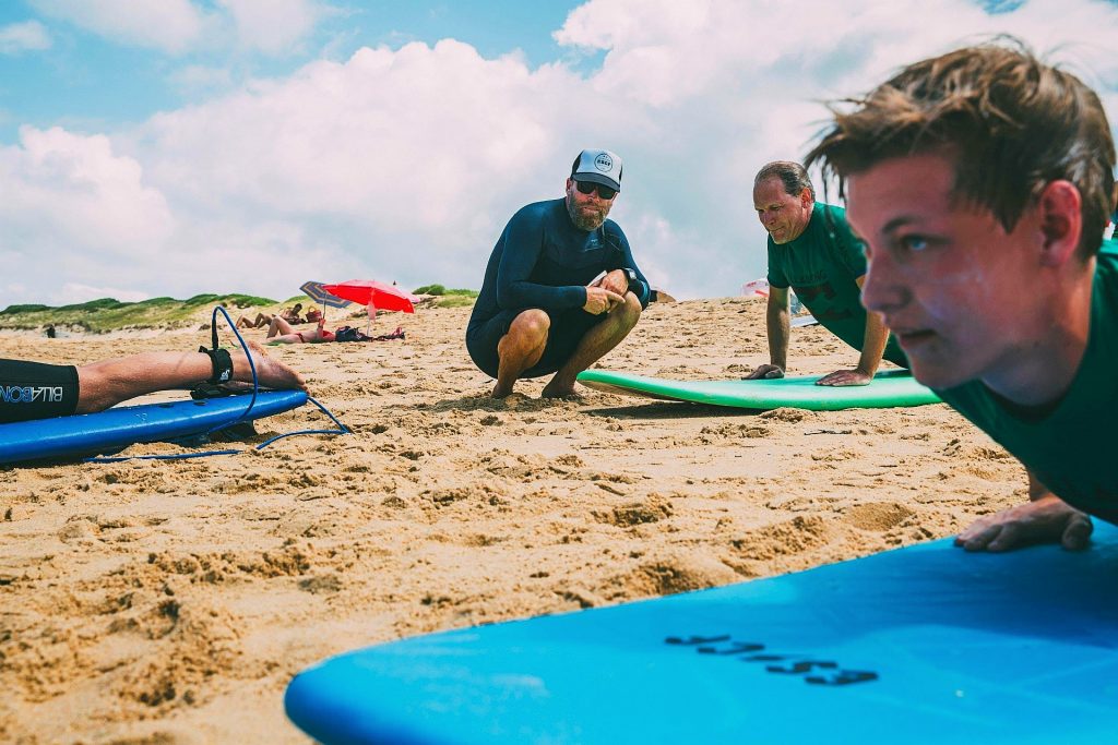 An instructor watches the group warm up during a surfing lesson in Anglet.