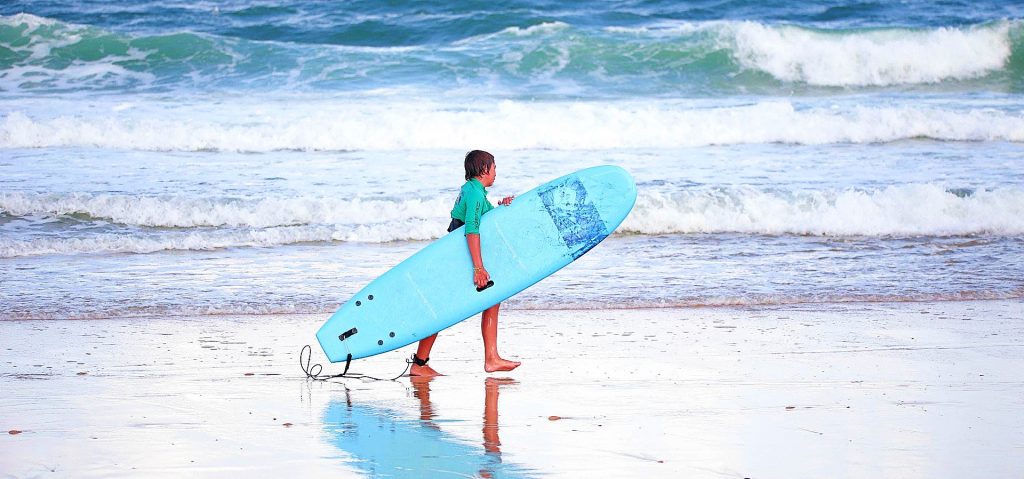 A guy walks out of the ocean after surfing lessons in Seignosse.