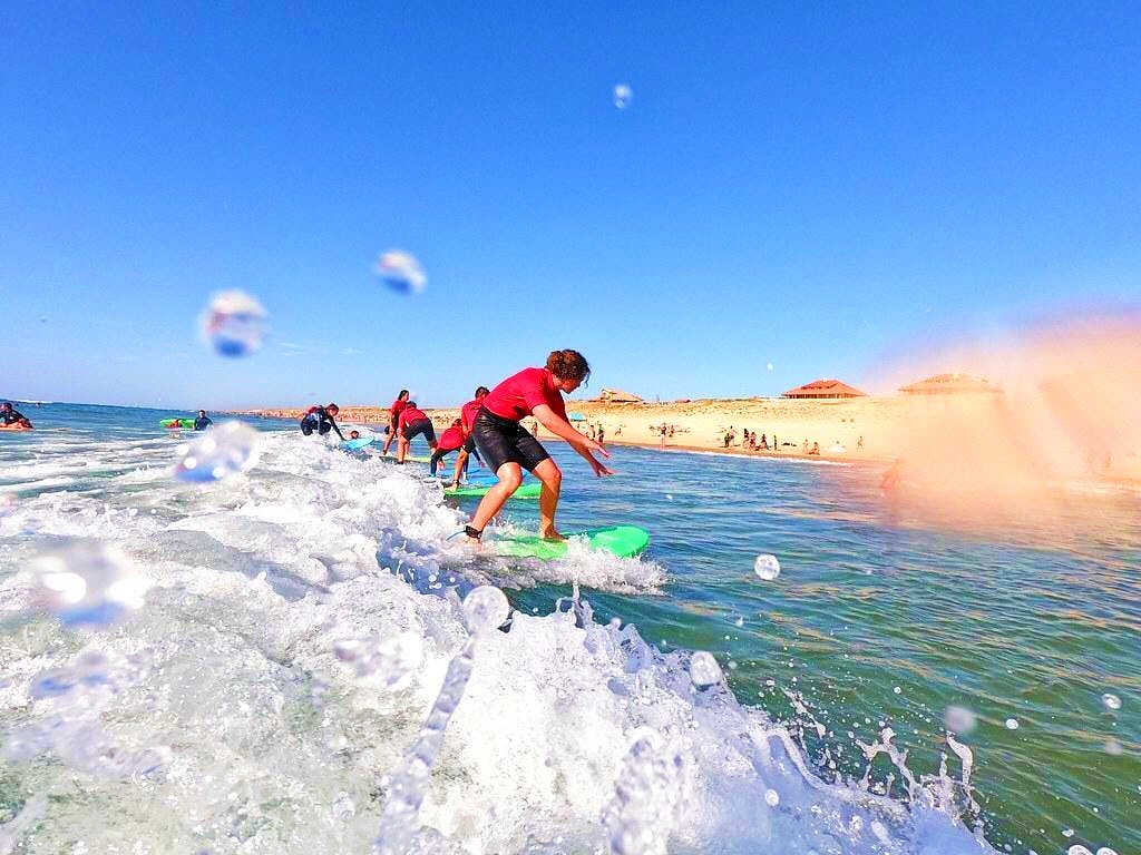 A group of teens ride their first waves during the surfing lessons in Vieux Boucau.