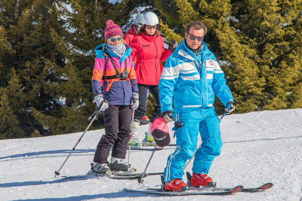 A group of adults learn to ski in Les Gets with the help of an instructor. 