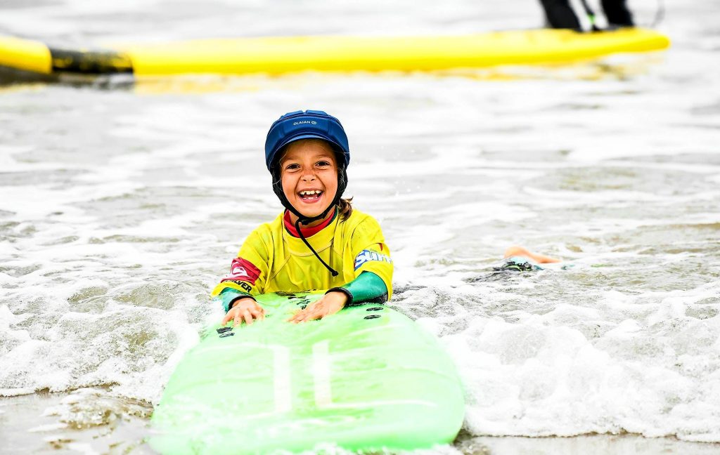 Une petite fille profite de ses cours de surf à Hendaye, le meilleur endroit pour les débutants en surf en France.