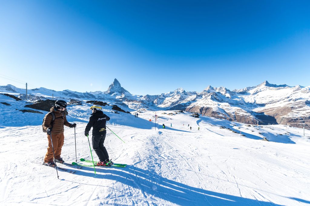 Two people learn to ski in Zermatt on an almost empty ski slope.