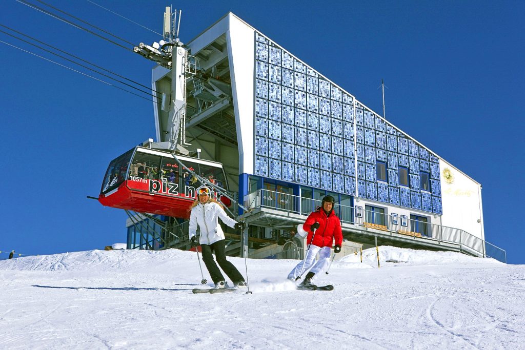 Covid-19 - ski schools in Switzerland: On the slopes, two people ski without a face mask, In the background the cableway, where the mask is mandatory.