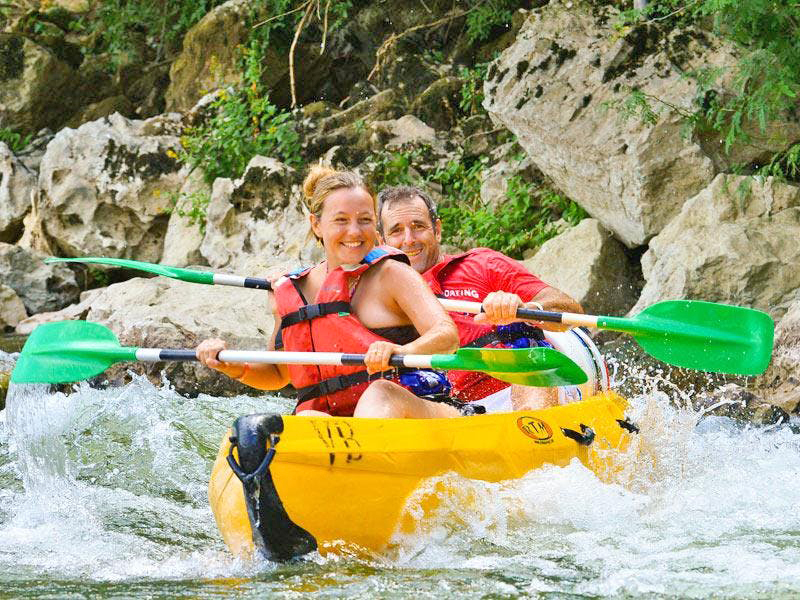 Deux personnes s'amusent pendant leur descente en canoë sur l'Ardèche.