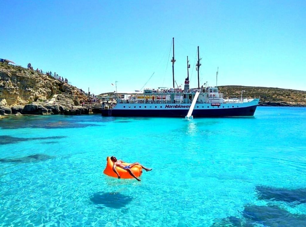 Un homme se détend dans le Blue Lagoon à Malte pendant une sortie en bateau.