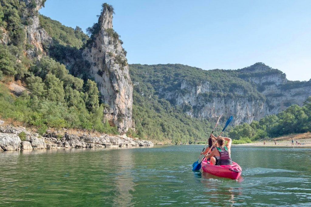 Ein Paar paddelt bei einer Kanutour auf der Ardèche den Fluss entlang.