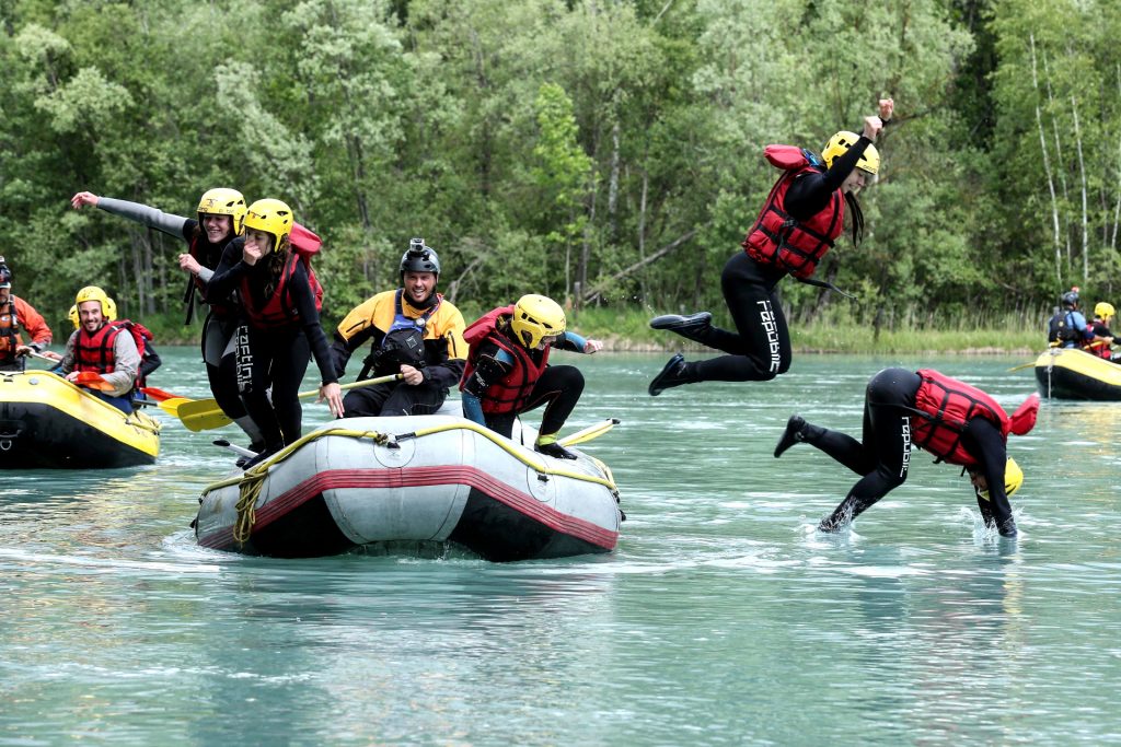Eine Gruppe springt von ihrem Raft-Boot ins Wasser.