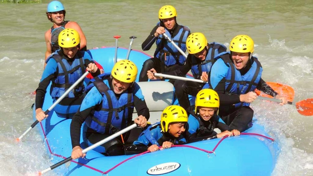 Eine Rafting-Tour auf dem Genil, bei der sich die Kinder am Boot festhalten, während die Erwachsenen fröhlich paddeln.