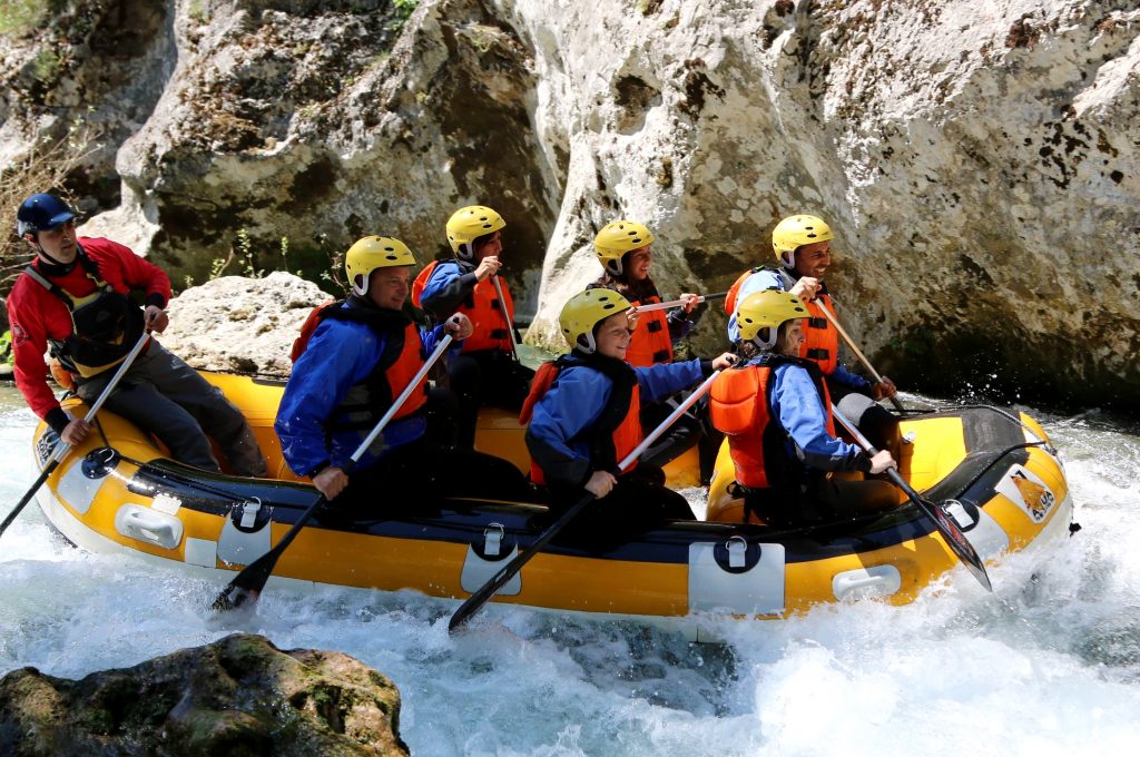 Eine Rafting-Gruppe paddelt mit ihrem Guide auf dem Lao.