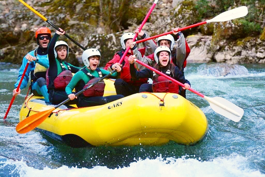 Kinder und ihr Guide sind auf ihrer Raftingtour auf dem Noguera Pallaresa vor einer starken Stromschnelle.