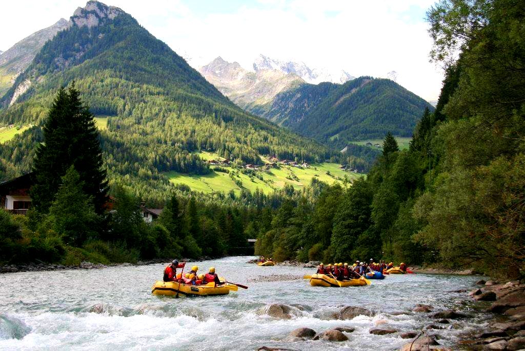 Eine Rafting-Gruppe bewundert die Berglandschaft im Hintergrund.