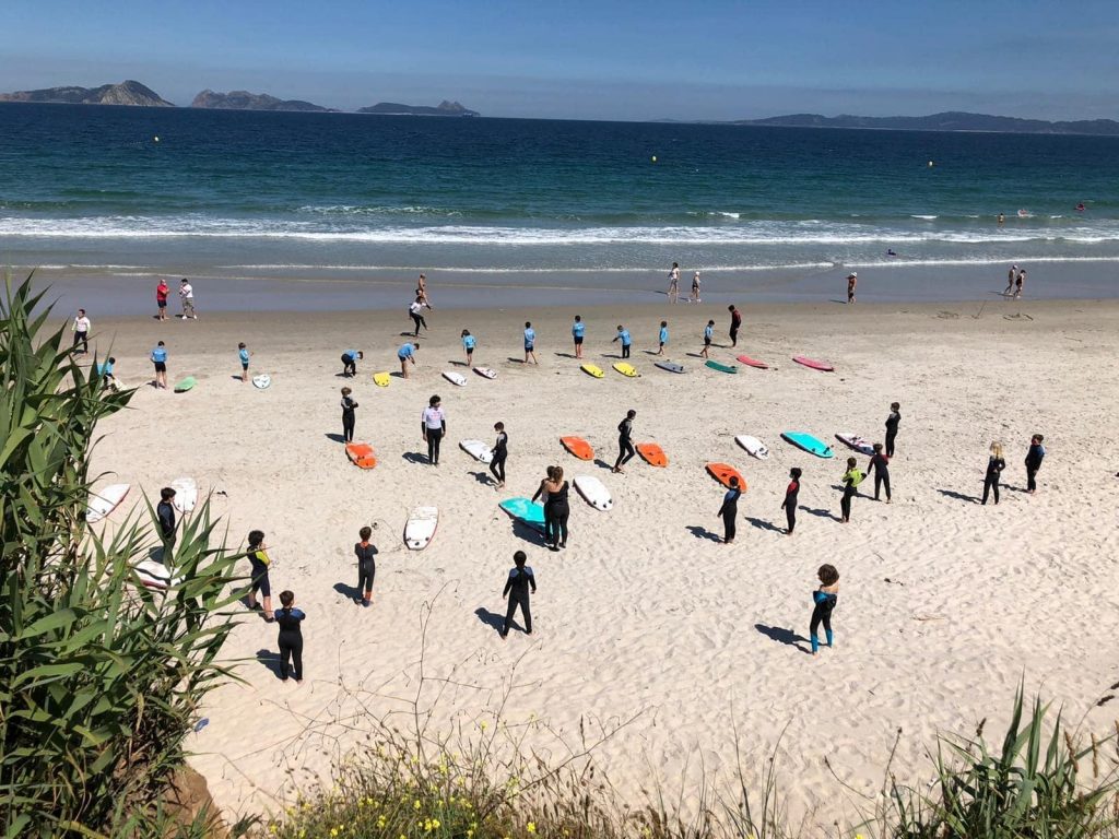 More groups of beginner surfers take part in a surf class on Praya La Lanzada beach.