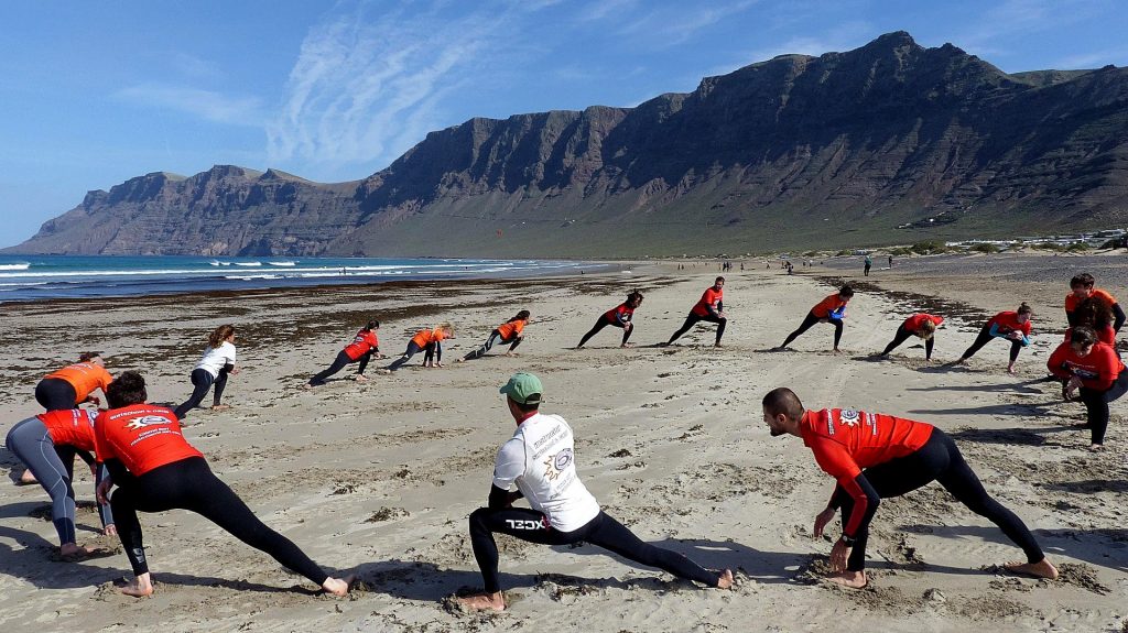 During a beginners' surfing lesson at Playa de Famara, participants are warming up.