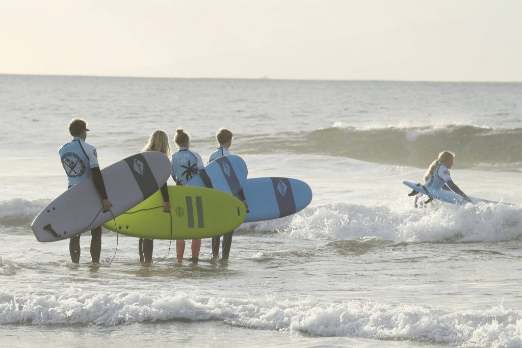 5 surfing beginners take part in a surfing class at Playa de Las Américas.