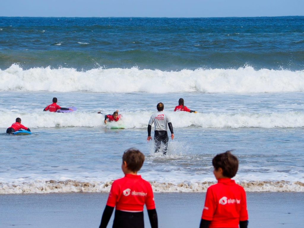 Two children are about to get into the water during a beginners' surfing class at Playa de Patos.