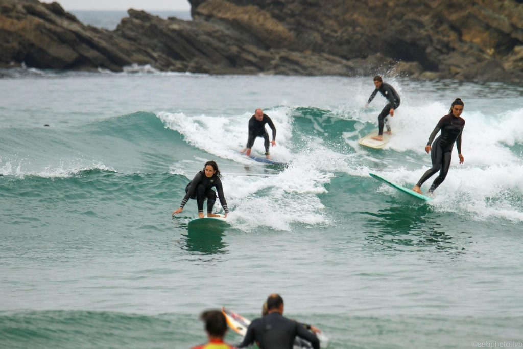 A group people train on the waves with a surfboard.