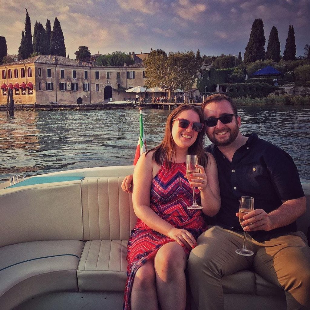 Una coppia fa una gita romantica in barca al Lago di Garda e prindano con del prosecco. 