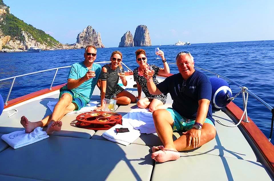 Zwei Paare stoßen mit Champagner auf ihre Bootstour in Sorrent an.
