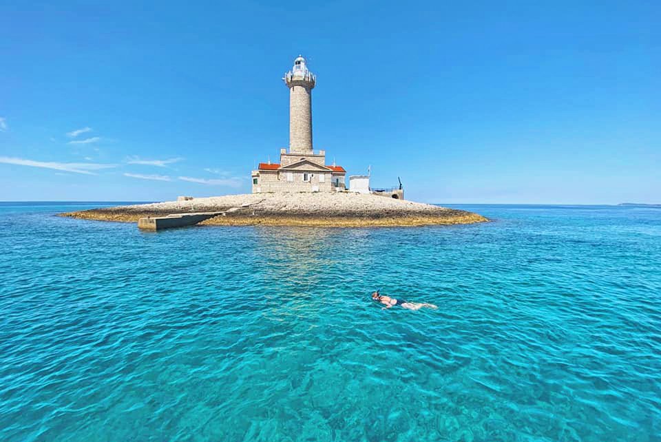 A lighthouse surrounded by water can be admired during a snorkelling excursion to Kap Kamenjak.