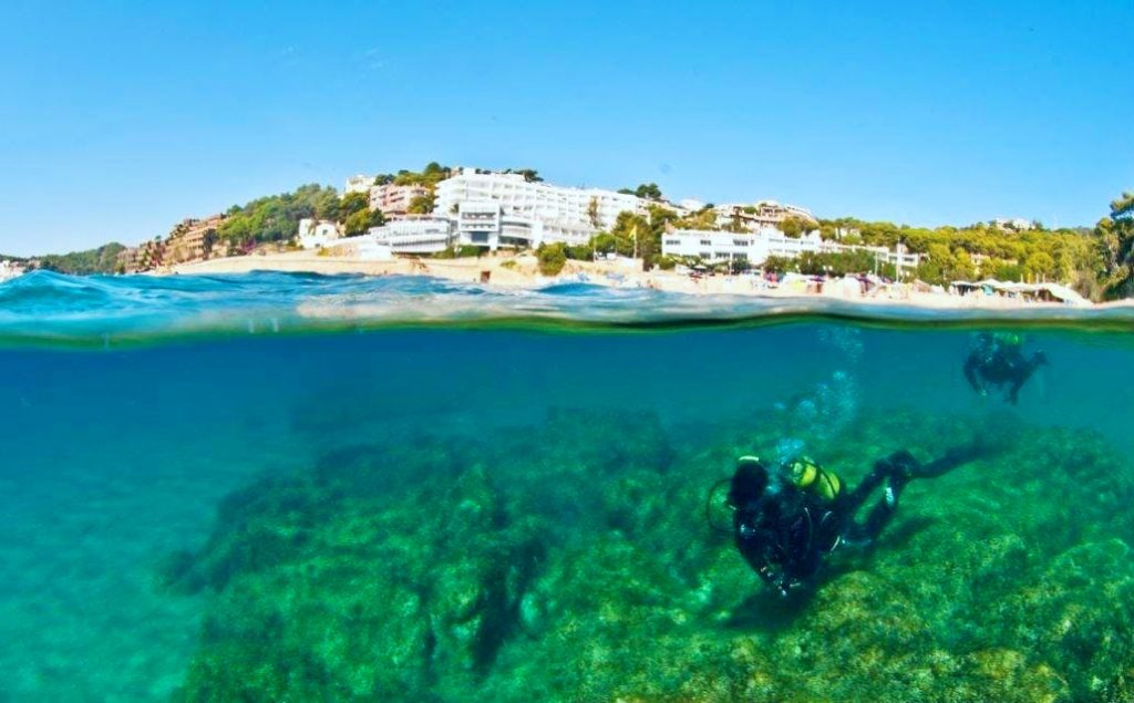 Two people are seen scuba diving in Spain, in Tossa de Mar.