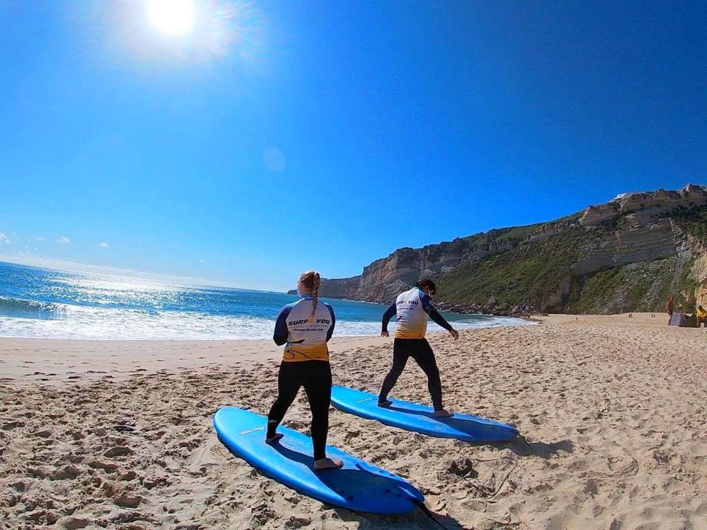 While surfing in Portugal, two people prepare for their lesson in Nazaré.