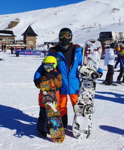 A kid is taking a private snowboarding lesson in Sierra Nevada ski resort in the village of Pradollano. 