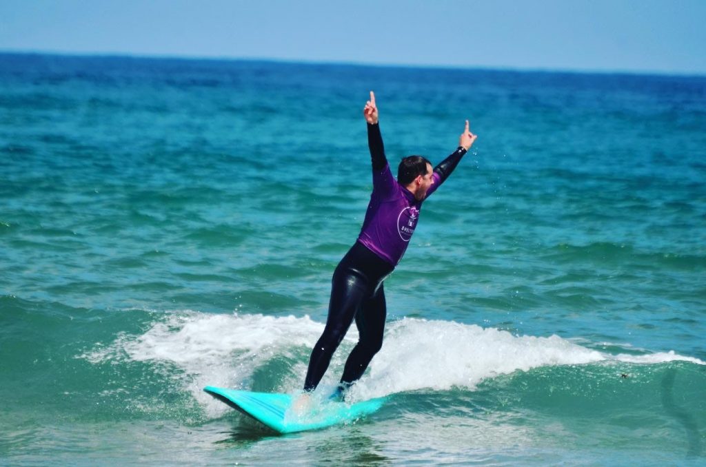 Ein Surfanfänger schafft es auf dem Surfbrett bei seiner ersten Surfstunde am Playa Zarautz in Spanien zu stehen.
