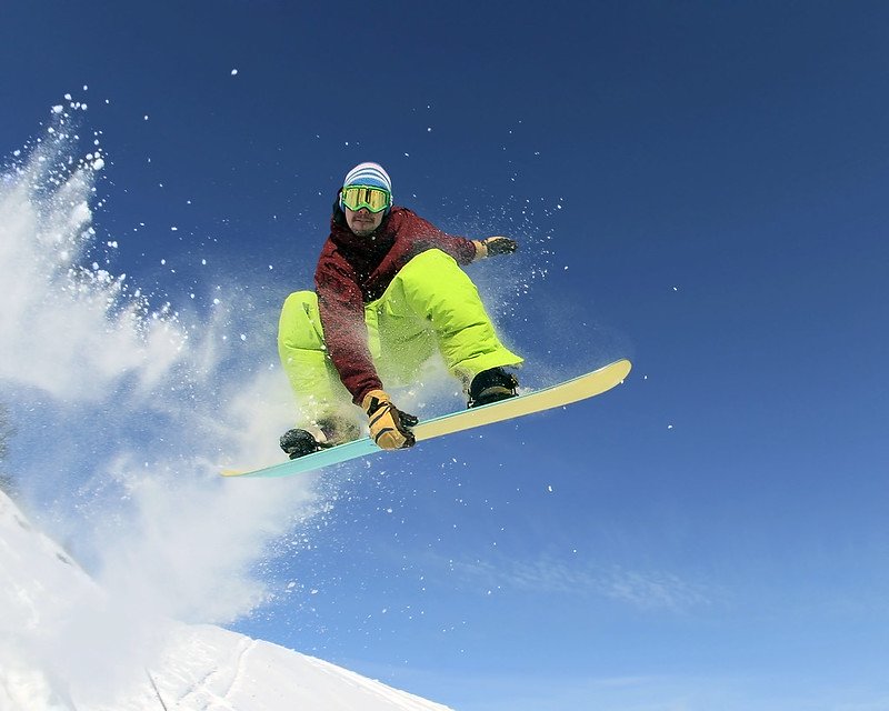 A snowboarder is doing some nice tricks on his snowboard during a day trip to La Pinilla from Madrid.