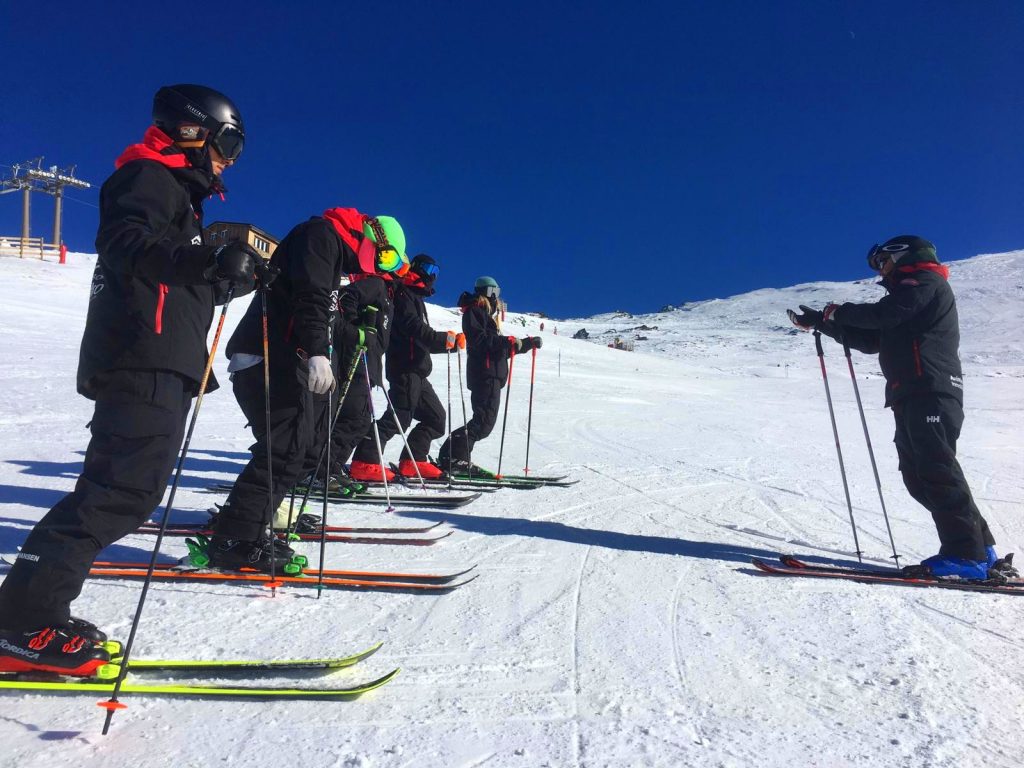 A group of adults take a ski lesson in Sierra Nevada mountains in Pradollano ski resort. 