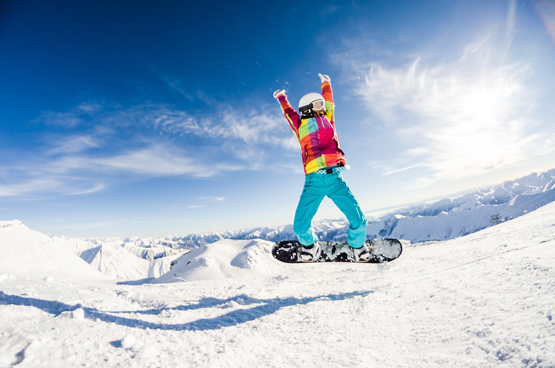 Ein Mädchen ist glücklich, weil es in den Weihnachtsferien das Snowboarden gelernt hat.