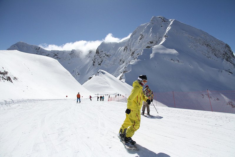 Ein Snowboarder fährt die Pisten hinunter, nachdem er im Unterricht mit Leihausrüstung das Snowboarden gelernt hat.