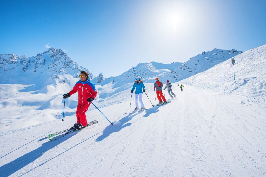 An instructor is leading the way during a group ski lesson.